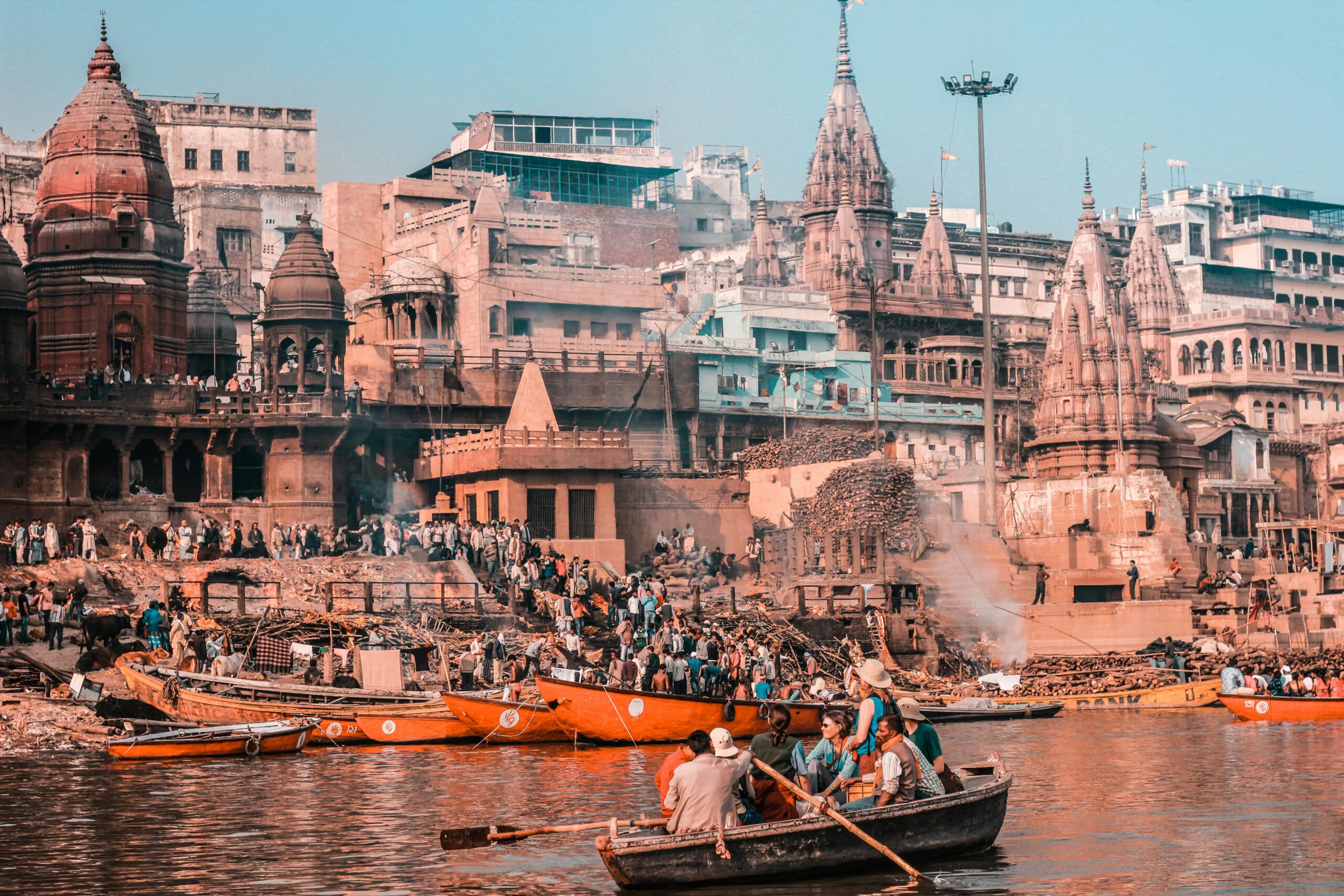 Bustling scene of Varanasi's riverfront with temples and boats on the Ganges River, capturing spirituality.
