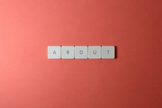 About Us Close-up of keyboard buttons spelling 'ABOUT' against a red surface, minimalist style.
