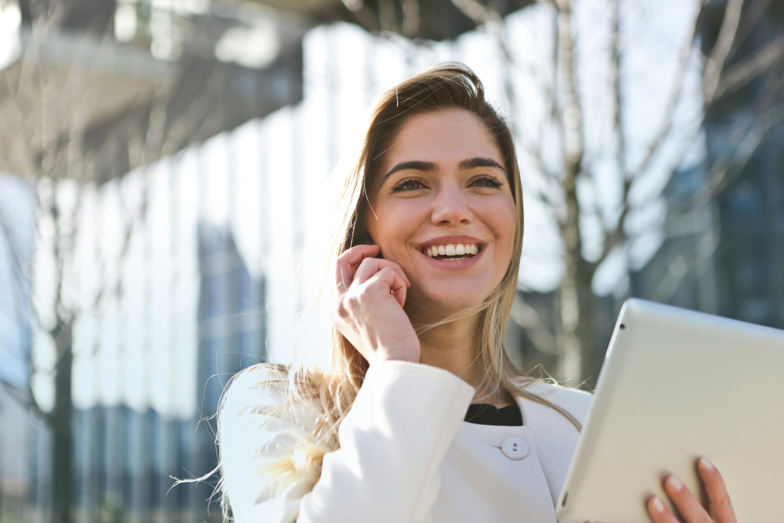 1 Call, Query Solve-Contact-Valiant Getaways and ask query,Confident businesswoman using her tablet and phone, smiling outdoors in sunlight.